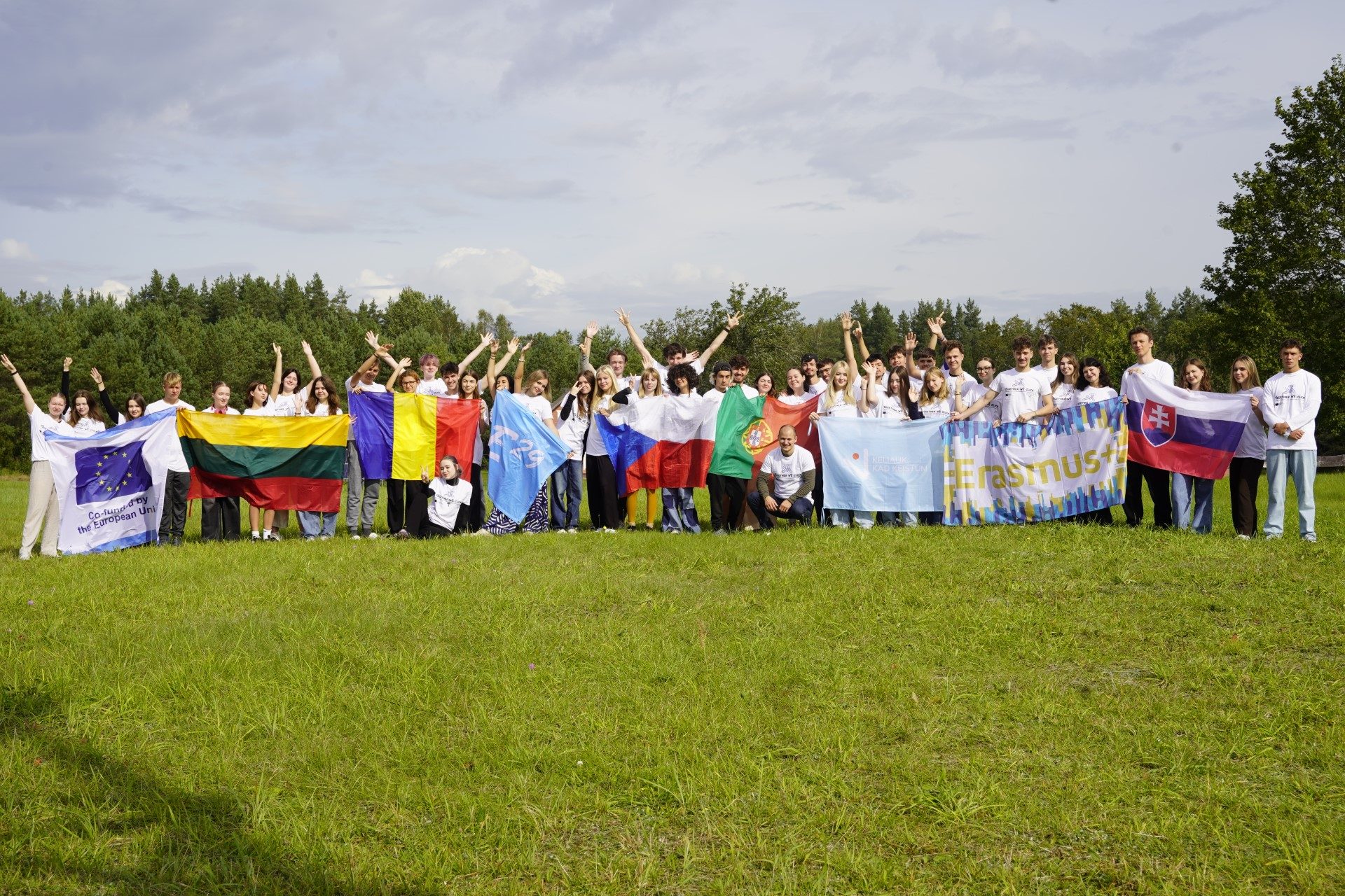 The whole group raises national flags in the field